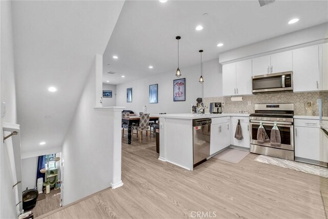 kitchen featuring appliances with stainless steel finishes, light wood-style flooring, white cabinetry, a peninsula, and recessed lighting