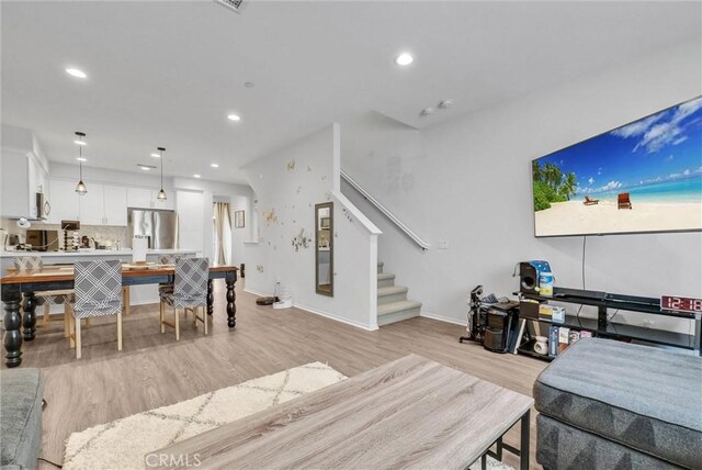 living room with light wood-style flooring, stairway, baseboards, and recessed lighting
