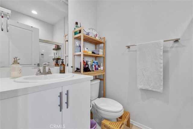 full bathroom with toilet, a shower with door, vanity, and baseboards