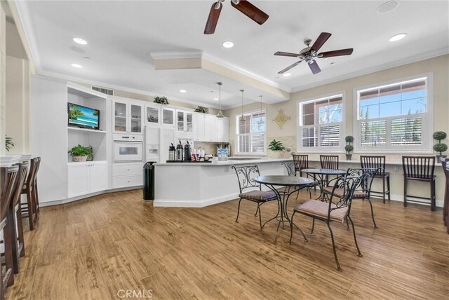 kitchen with oven, ceiling fan, ornamental molding, a peninsula, and white cabinets