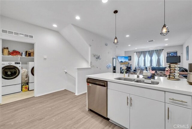 kitchen with stainless steel dishwasher, washing machine and clothes dryer, a sink, light wood finished floors, and light countertops