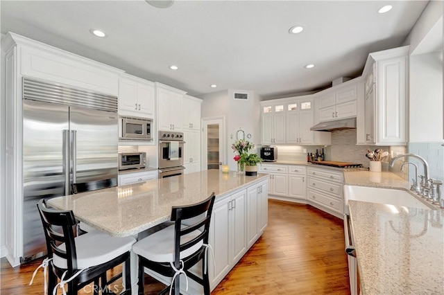 6288 Sunnyside Cir, Huntington Beach, CA 92648 - kitchen featuring visible vents, white cabinets, built in appliances, a sink, and light wood-style flooring