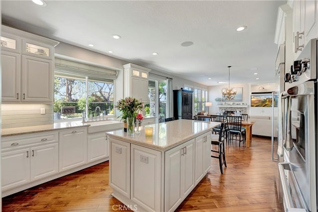 6288 Sunnyside Cir, Huntington Beach, CA 92648 - kitchen with a sink, white cabinetry, a kitchen island, and light wood-style floors