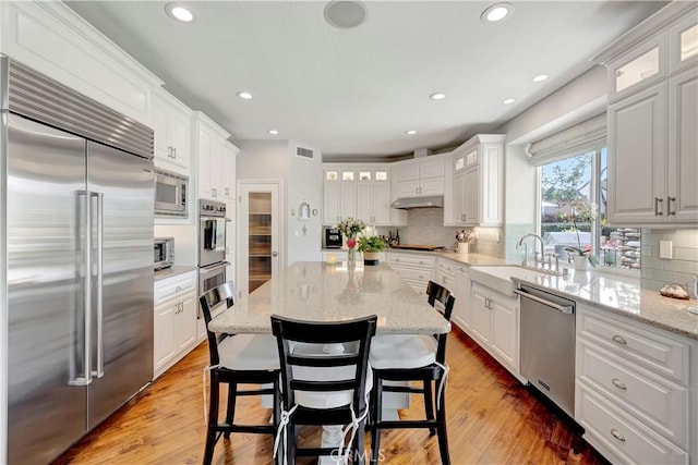 6288 Sunnyside Cir, Huntington Beach, CA 92648 - kitchen featuring visible vents, under cabinet range hood, a sink, light wood finished floors, and built in appliances