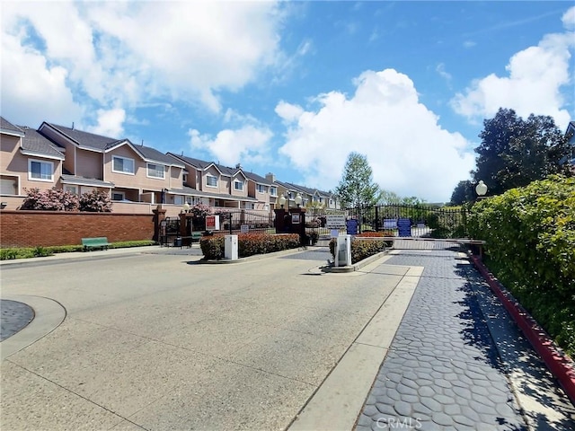 view of street featuring a gate, a residential view, a gated entry, and curbs