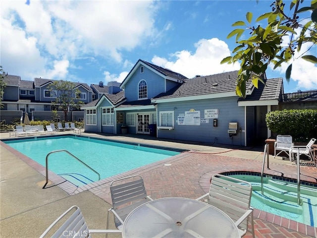 pool featuring fence, a community hot tub, a patio, and french doors
