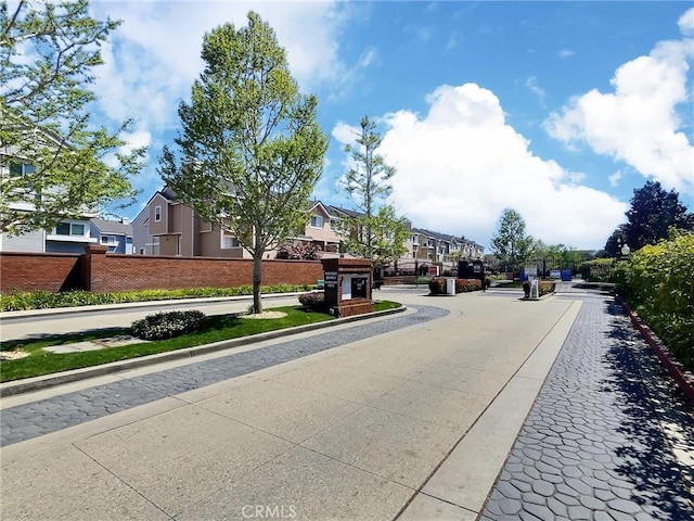 view of street featuring a gated entry, curbs, sidewalks, and a residential view