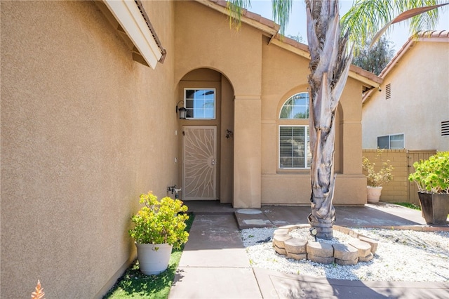 doorway to property with a patio, stucco siding, and fence