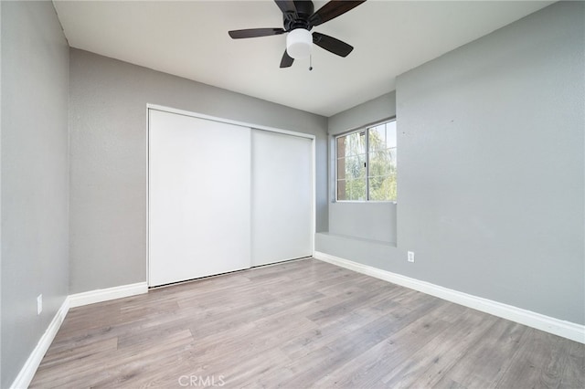 unfurnished bedroom with a closet, baseboards, ceiling fan, and wood finished floors