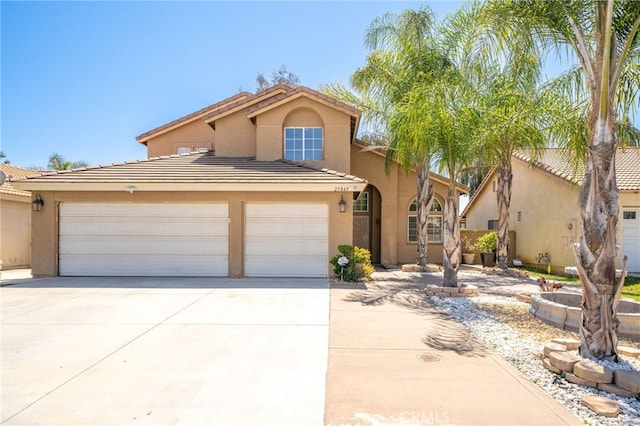 mediterranean / spanish home with a tile roof, an attached garage, stucco siding, and concrete driveway