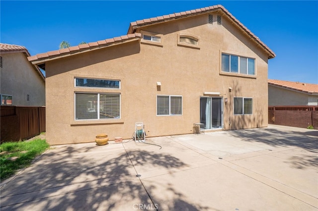 rear view of property with fence, a patio, and stucco siding