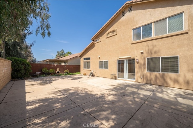 rear view of house with a patio, stucco siding, and a fenced backyard