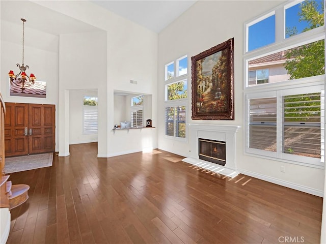 125 Heath Meadow Pl, Simi Valley, CA 93065 - unfurnished living room featuring a chandelier, plenty of natural light, dark wood-style flooring, a glass covered fireplace, and a towering ceiling