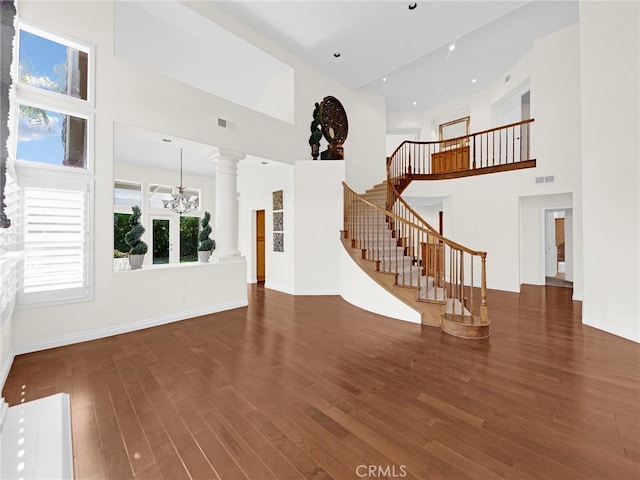 125 Heath Meadow Pl, Simi Valley, CA 93065 - unfurnished living room featuring a towering ceiling, stairway, a chandelier, wood finished floors, and ornate columns