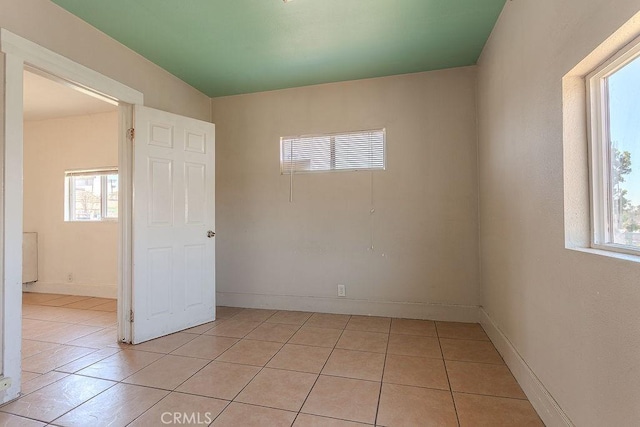empty room featuring light tile patterned flooring, baseboards, and a wealth of natural light
