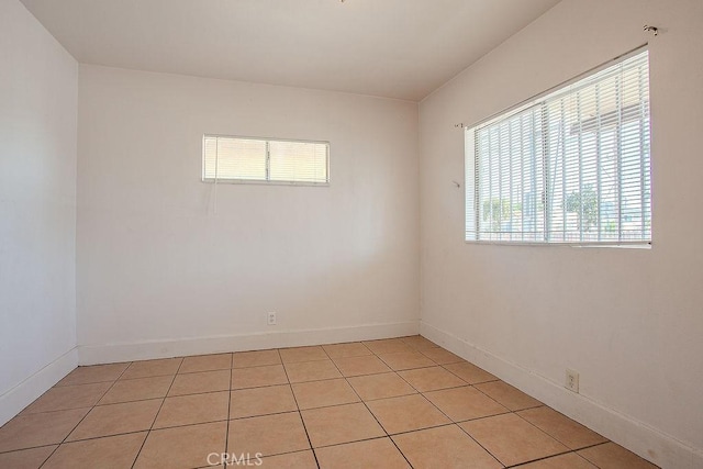empty room featuring light tile patterned floors and baseboards