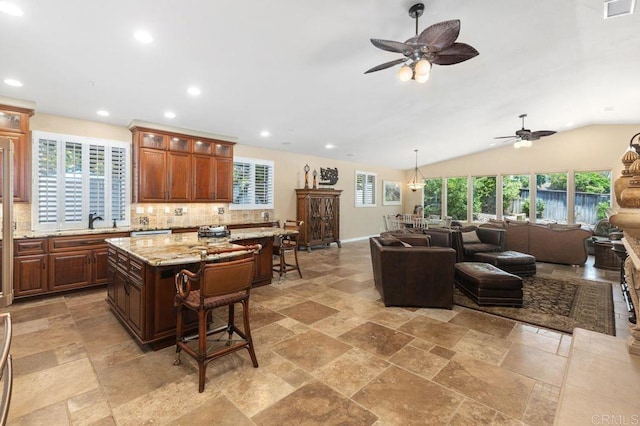 1034 Via Reata, Vista, CA 92081 - kitchen with open floor plan, ceiling fan, a kitchen breakfast bar, and stone tile floors