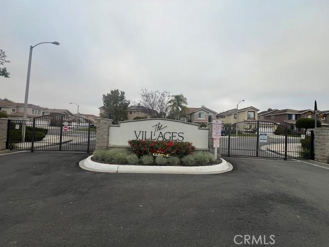 community sign with aphalt driveway, a residential view, and a gate