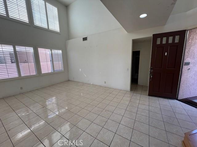 empty room featuring plenty of natural light, light tile patterned floors, and a towering ceiling