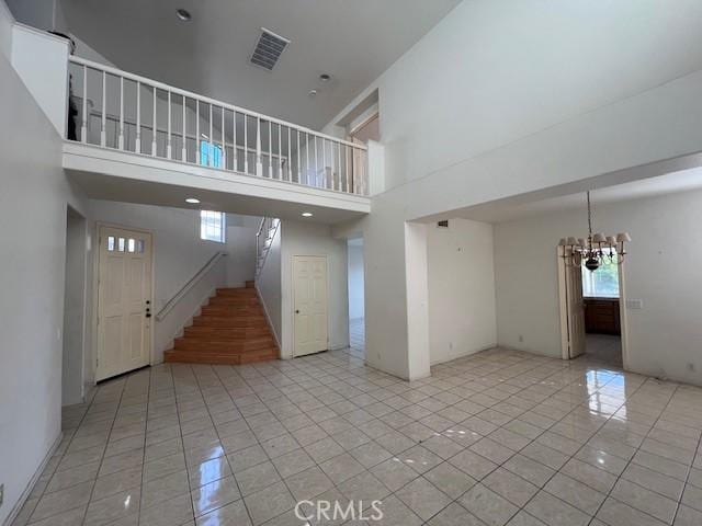 unfurnished living room featuring a chandelier, a healthy amount of sunlight, light tile patterned floors, and visible vents