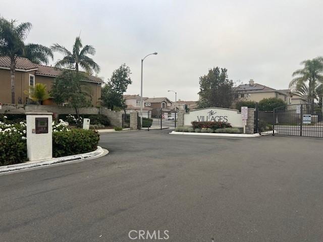 view of street featuring a residential view, a gated entry, curbs, and a gate