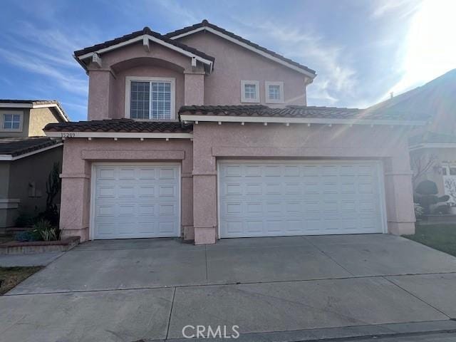 view of front of property featuring a tiled roof, driveway, stucco siding, and a garage