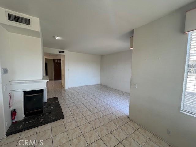 unfurnished living room with visible vents, a fireplace with raised hearth, and light tile patterned floors
