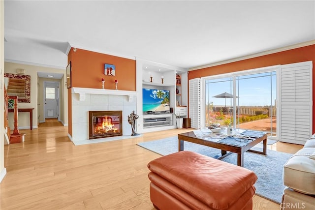 4612 Wolfe Way, Woodland Hills, CA 91364 - living room with ornamental molding, a tiled fireplace, light wood finished floors, baseboards, and built in shelves