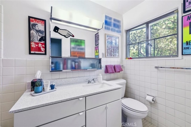 bathroom with toilet, vanity, and tile walls