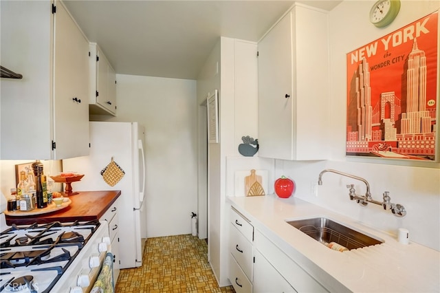 kitchen featuring a sink, light countertops, white range with gas cooktop, and white cabinets