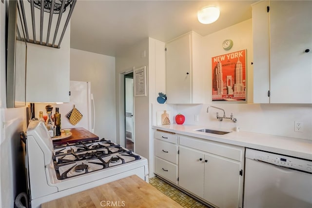 kitchen with white appliances, light countertops, a sink, and white cabinetry