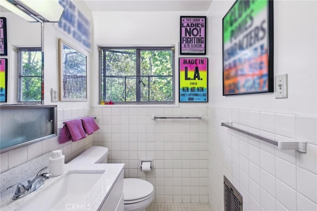 bathroom featuring a wealth of natural light, vanity, tile walls, and toilet