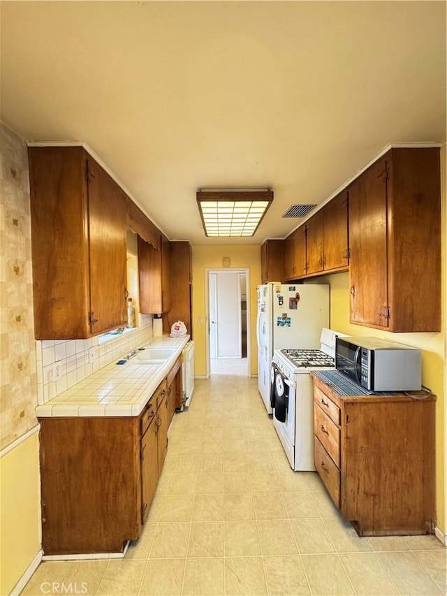 kitchen featuring visible vents, a sink, stainless steel microwave, baseboards, and white range with gas cooktop