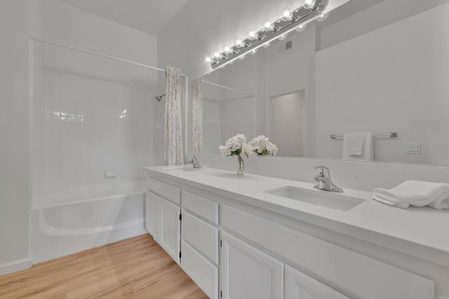 bathroom featuring shower / bathtub combination with curtain, visible vents, a sink, and wood finished floors