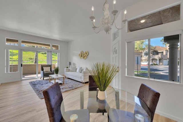 dining space with baseboards, an inviting chandelier, and light wood-style floors