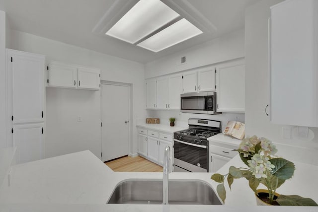 kitchen featuring light countertops, white cabinetry, a sink, and appliances with stainless steel finishes