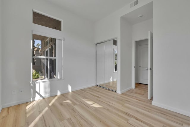 unfurnished bedroom with visible vents, light wood-style flooring, a closet, and baseboards