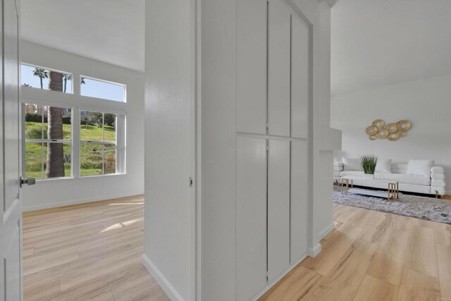 corridor with light wood finished floors and baseboards