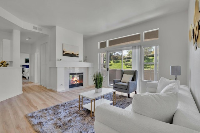 living area with visible vents, a tile fireplace, and wood finished floors