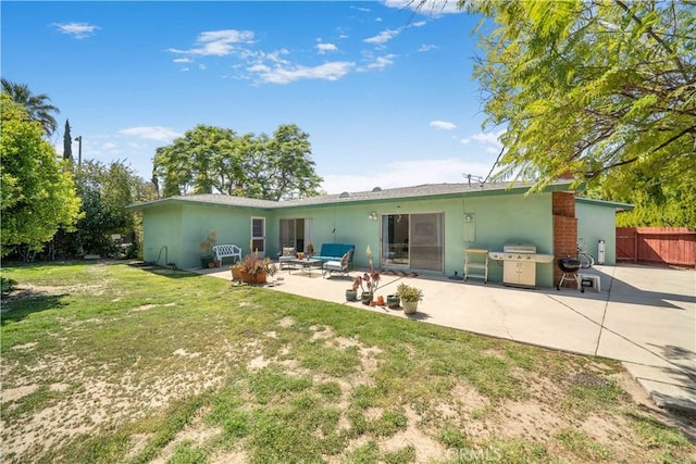 rear view of house with a patio, a yard, stucco siding, and fence
