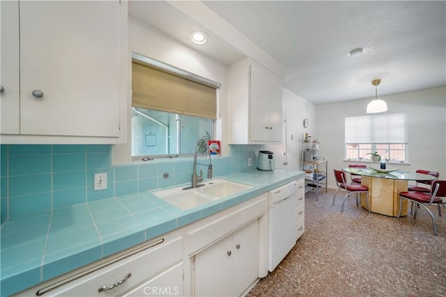 kitchen featuring tile countertops, dishwasher, a sink, and white cabinetry