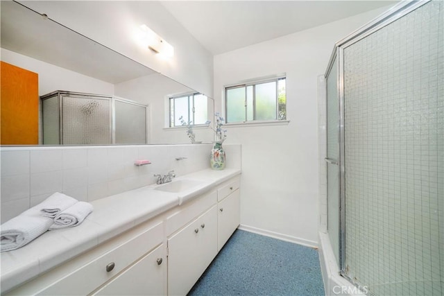 bathroom featuring backsplash, baseboards, a stall shower, and vanity