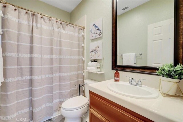 full bathroom featuring visible vents, toilet, curtained shower, and vanity