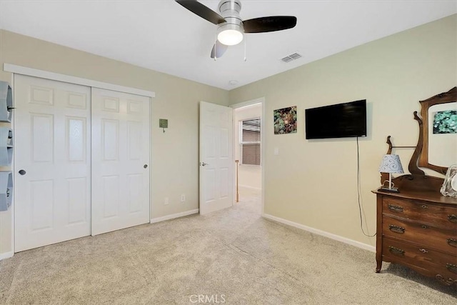 carpeted bedroom featuring a closet, visible vents, baseboards, and ceiling fan