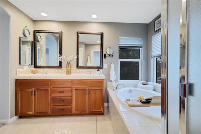 bathroom featuring a bath, double vanity, a sink, and tile patterned floors
