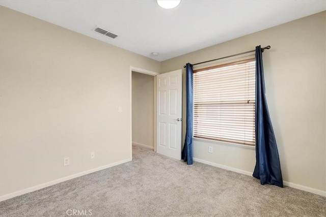 carpeted empty room featuring baseboards and visible vents