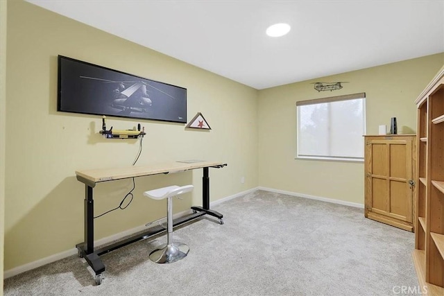 office area featuring baseboards and light carpet