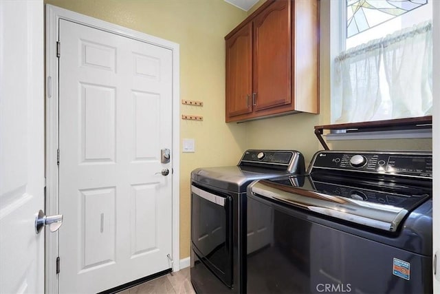 washroom with cabinet space, baseboards, and washing machine and dryer