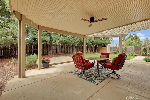 view of patio with an outbuilding, a fenced backyard, a ceiling fan, a storage unit, and outdoor dining area