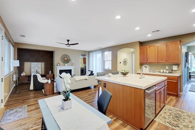 kitchen with a sink, tile counters, ceiling fan, and arched walkways